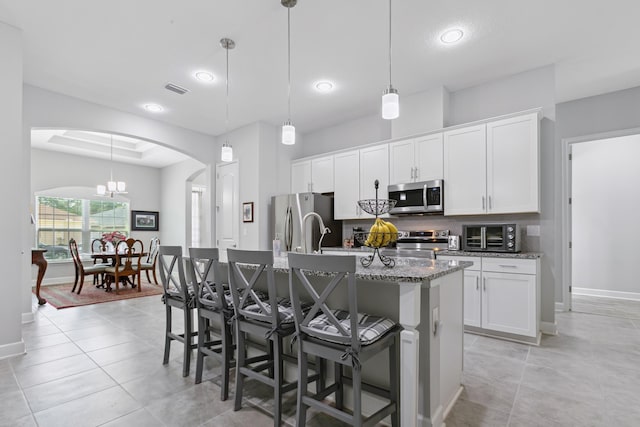 279 Spring Creek Way, Saint Augustine, FL 32095 - kitchen with appliances with stainless steel finishes, arched walkways, a breakfast bar area, a kitchen island with sink, and white cabinetry