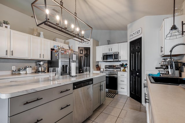 3010 SE 46th Ave, Ocala, FL 34480 - kitchen featuring appliances with stainless steel finishes, a sink, light tile patterned floors, white cabinets, and decorative light fixtures