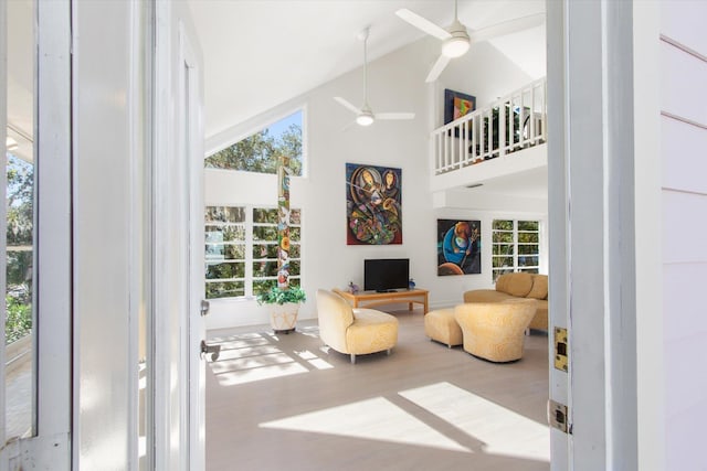 living area featuring ceiling fan, plenty of natural light, high vaulted ceiling, and light hardwood / wood-style floors