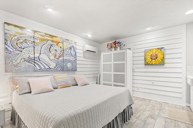 bedroom featuring hardwood / wood-style flooring and a wall mounted AC