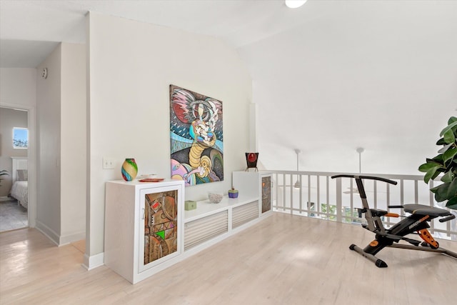 corridor with lofted ceiling, a wealth of natural light, and light hardwood / wood-style floors