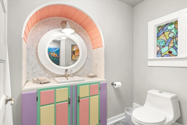 bathroom with vanity, toilet, and decorative backsplash