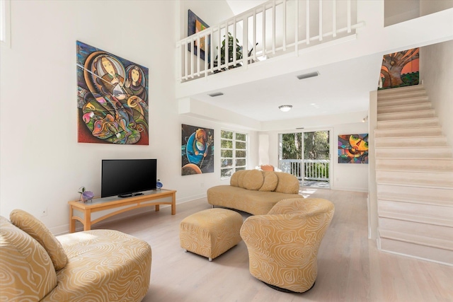 living room with a towering ceiling and hardwood / wood-style flooring