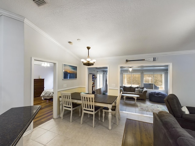 tiled dining area featuring vaulted ceiling, crown molding, a chandelier, and a textured ceiling