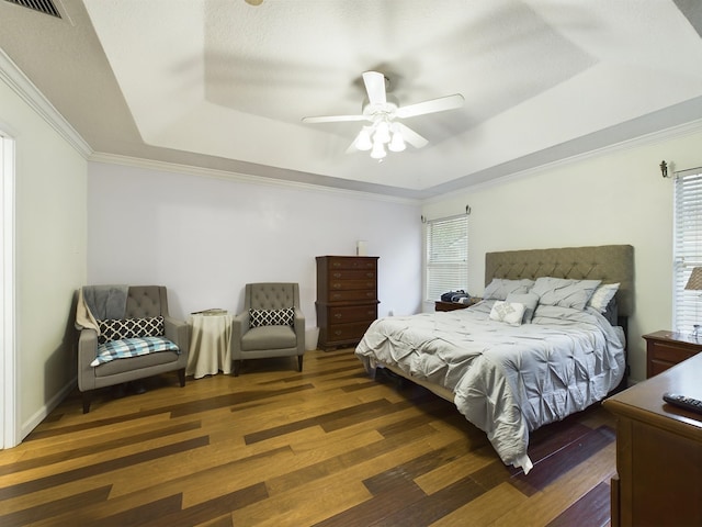 bedroom featuring crown molding, dark wood-type flooring, a raised ceiling, and ceiling fan