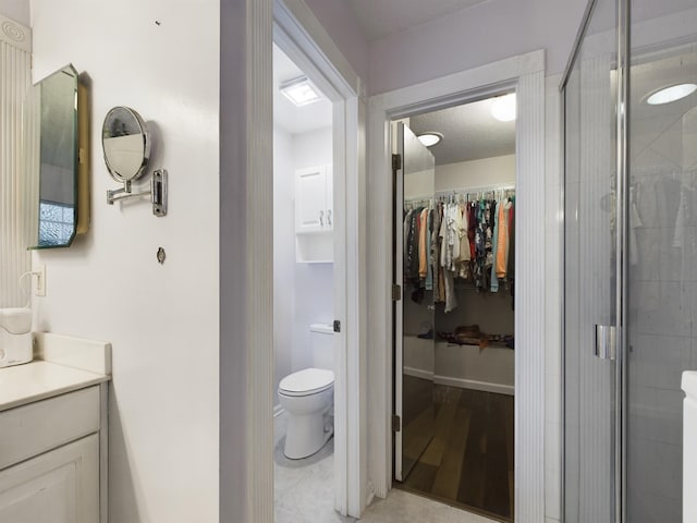 bathroom with tile patterned floors, toilet, a textured ceiling, vanity, and a shower with door