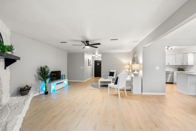 living room featuring light wood finished floors, ceiling fan, visible vents, and baseboards