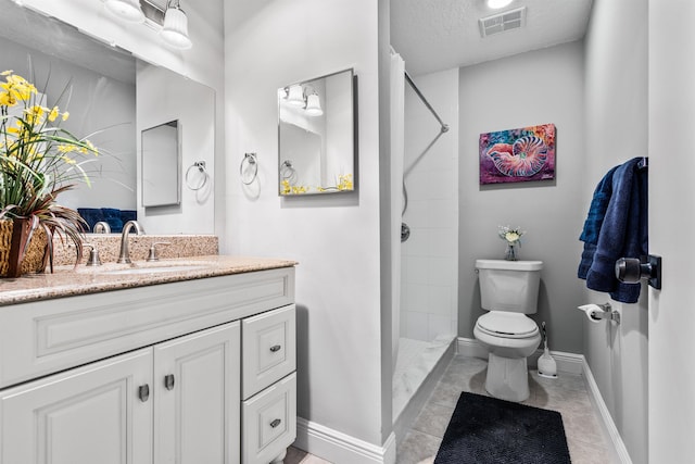 bathroom with visible vents, toilet, vanity, tiled shower, and baseboards