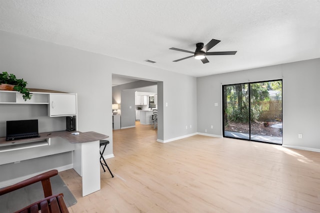 unfurnished office with a textured ceiling, ceiling fan, visible vents, and light wood-style flooring