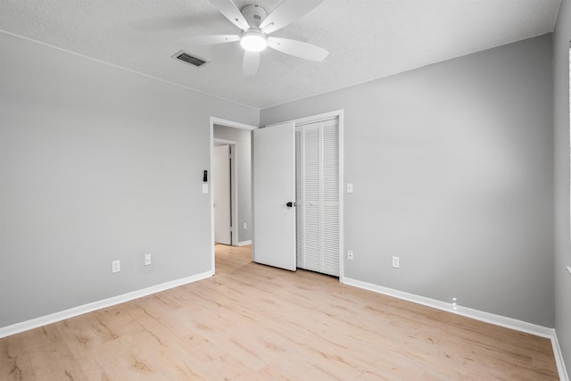 unfurnished room with visible vents, ceiling fan, a textured ceiling, wood finished floors, and baseboards