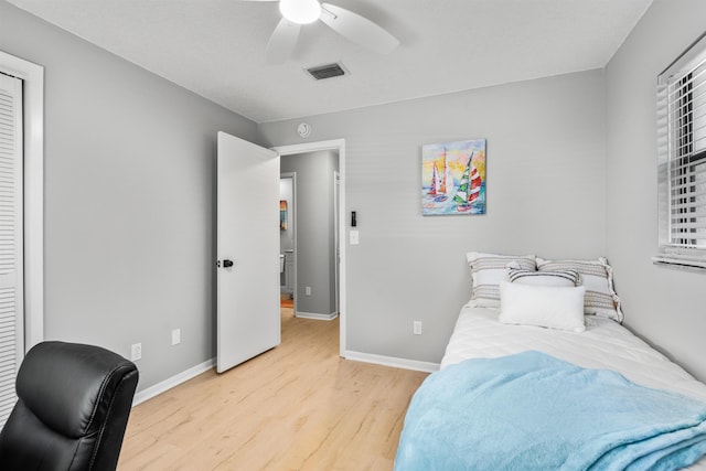 bedroom with light wood-style floors, visible vents, ceiling fan, and baseboards