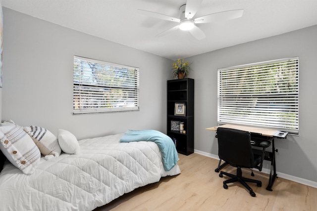 bedroom with a ceiling fan, baseboards, and light wood finished floors