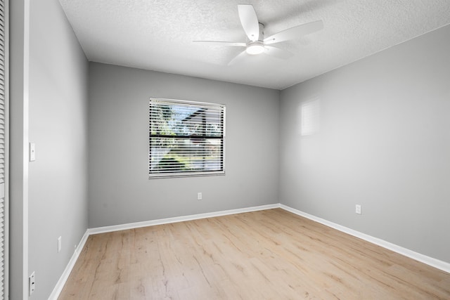 empty room featuring a textured ceiling, baseboards, a ceiling fan, and wood finished floors