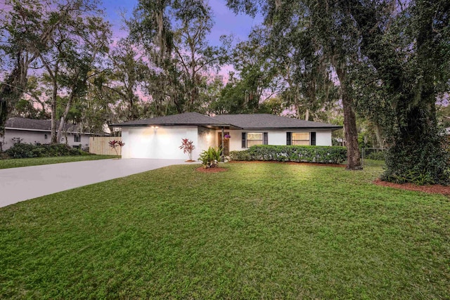 ranch-style home with driveway, a garage, a lawn, fence, and stucco siding