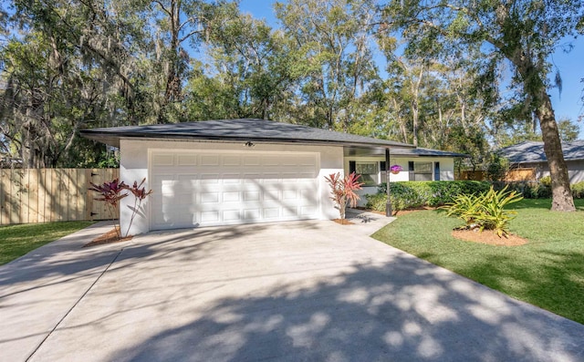 ranch-style house featuring a garage, concrete driveway, stucco siding, fence, and a front yard