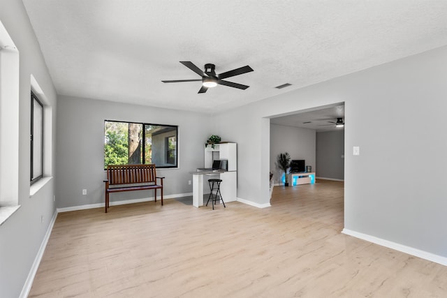 interior space with baseboards, ceiling fan, light wood-style flooring, and a textured ceiling