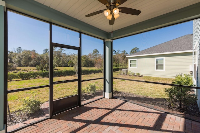 unfurnished sunroom featuring wood ceiling, ceiling fan, and plenty of natural light