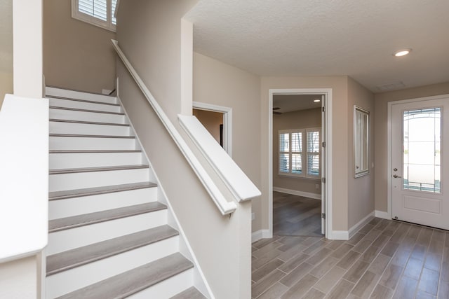 entryway with a textured ceiling, plenty of natural light, and wood-type flooring