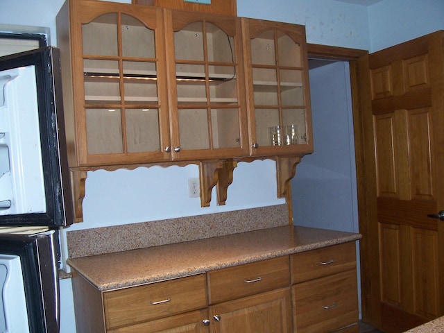 detailed view of glass insert cabinets, light countertops, and brown cabinetry