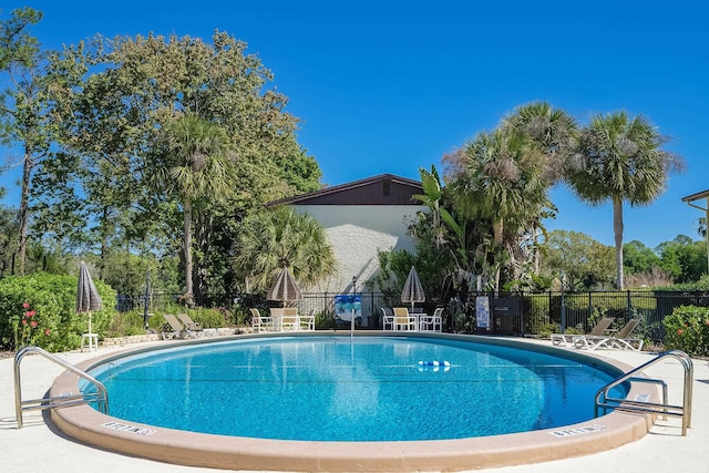 community pool with fence and a patio