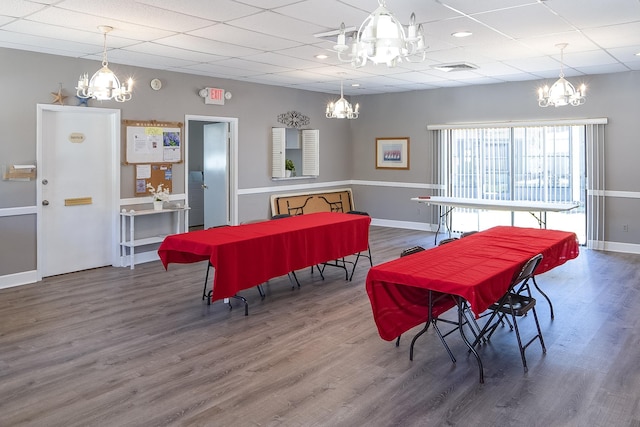 dining area with a chandelier, wood finished floors, a paneled ceiling, and baseboards