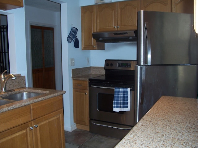 kitchen featuring under cabinet range hood, electric range, a sink, freestanding refrigerator, and light stone counters