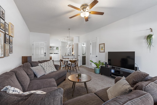 carpeted living room with washer / dryer, ceiling fan with notable chandelier, and sink