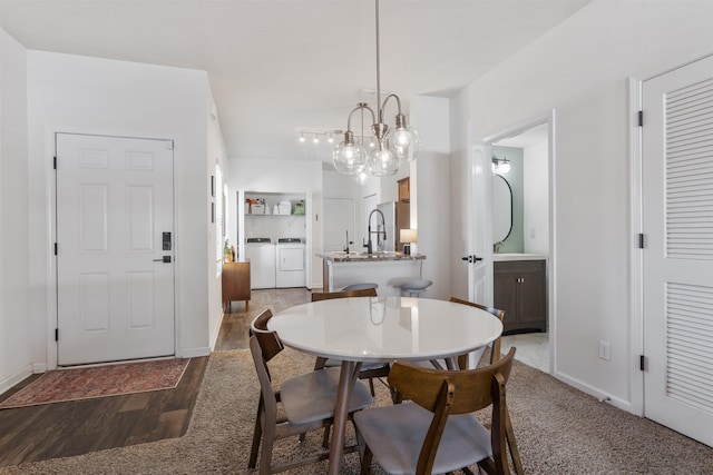 dining area featuring dark hardwood / wood-style flooring, a chandelier, and independent washer and dryer