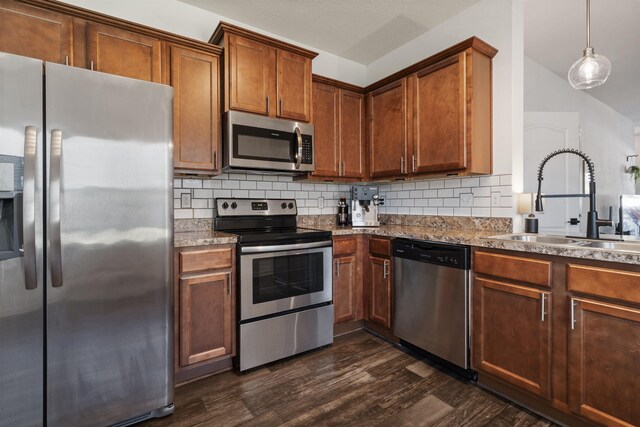 kitchen featuring appliances with stainless steel finishes, dark hardwood / wood-style floors, sink, decorative light fixtures, and backsplash