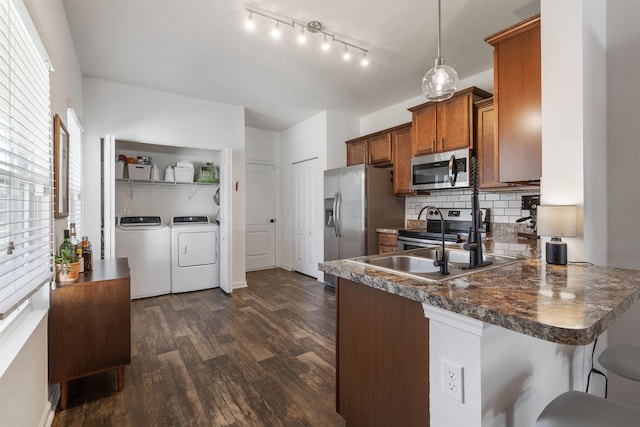 kitchen featuring separate washer and dryer, kitchen peninsula, dark hardwood / wood-style floors, pendant lighting, and appliances with stainless steel finishes