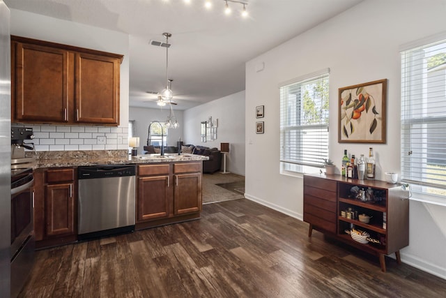 kitchen with stainless steel appliances, light stone countertops, dark hardwood / wood-style flooring, sink, and tasteful backsplash