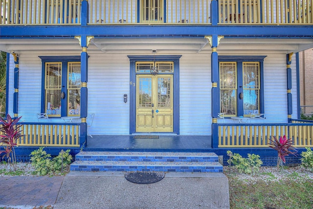 view of exterior entry featuring covered porch and a balcony