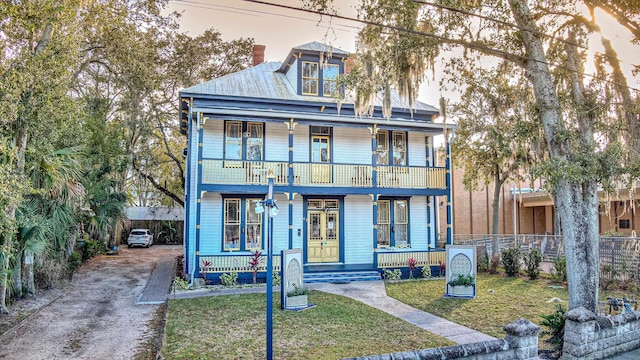 view of front of home with covered porch, a yard, and a balcony