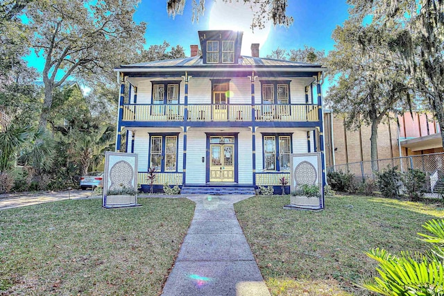 view of front of property featuring a balcony and a front lawn