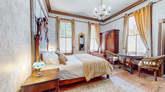 bedroom with a notable chandelier, light hardwood / wood-style floors, and ornamental molding