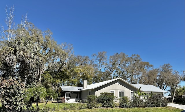 104 Falcon Rd, Saint Augustine, FL 32086 - view of side of property featuring a chimney, metal roof, and a sunroom