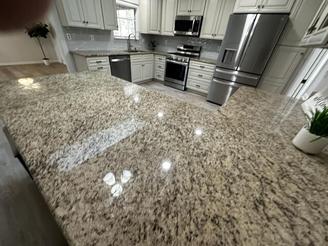 104 Falcon Rd, Saint Augustine, FL 32086 - kitchen with stainless steel appliances, a sink, light stone countertops, light wood finished floors, and backsplash