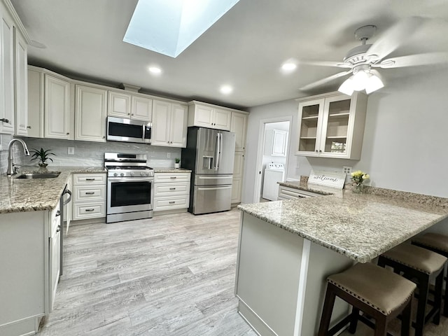 104 Falcon Rd, Saint Augustine, FL 32086 - kitchen with stainless steel appliances, washer / dryer, a sink, a peninsula, and light stone countertops