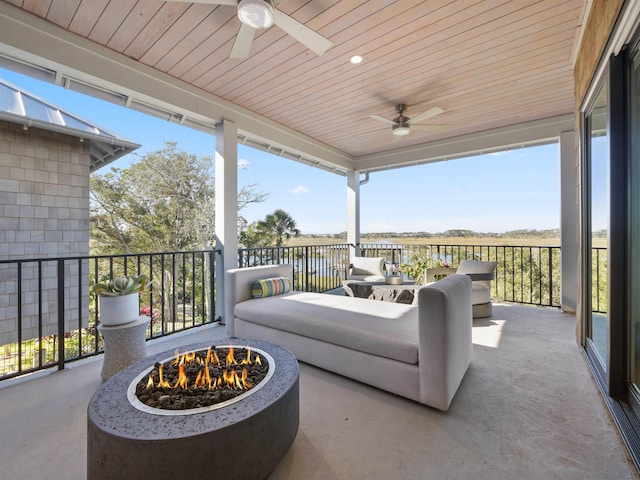 view of patio with ceiling fan and an outdoor living space with a fire pit