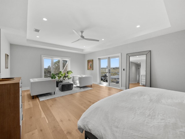 bedroom with access to outside, multiple windows, ceiling fan, and a raised ceiling