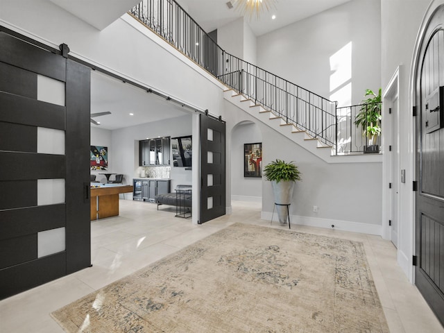 tiled foyer entrance with a high ceiling and a barn door