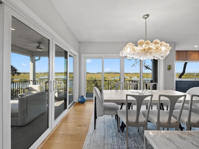 sunroom featuring ceiling fan with notable chandelier and a water view