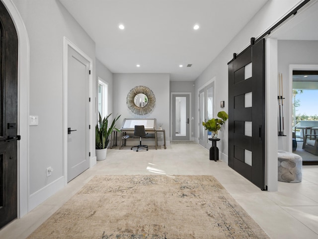 foyer entrance with a barn door and light tile patterned floors