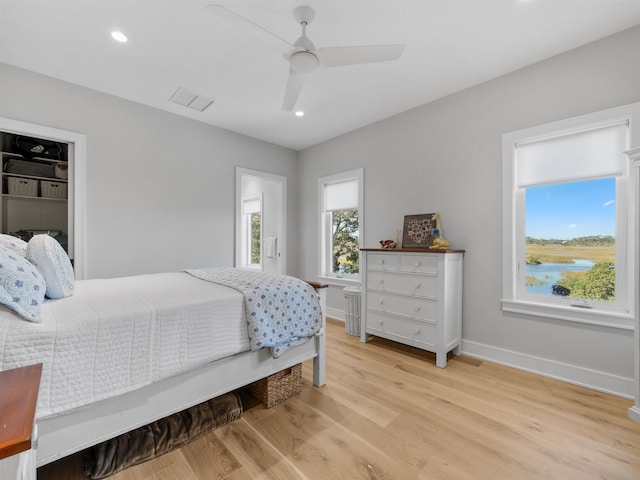 bedroom featuring ceiling fan, a water view, and light hardwood / wood-style flooring