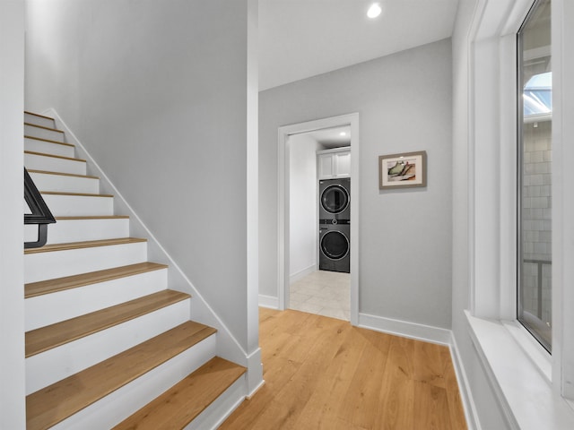 stairway with hardwood / wood-style floors and stacked washer / drying machine