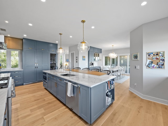 kitchen with pendant lighting, sink, an island with sink, light hardwood / wood-style floors, and stainless steel appliances