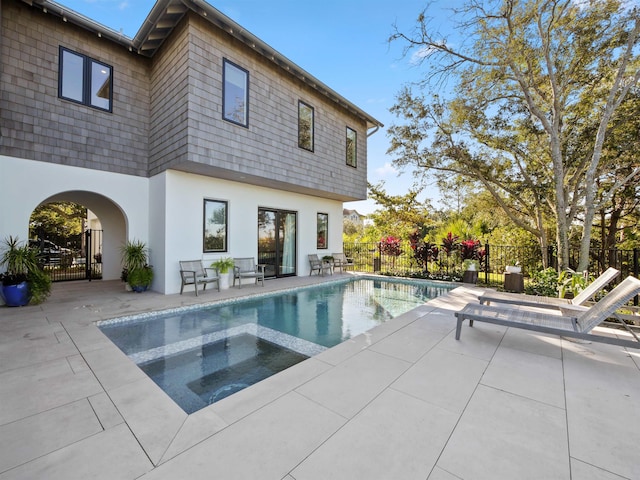 rear view of property with a pool with hot tub and a patio