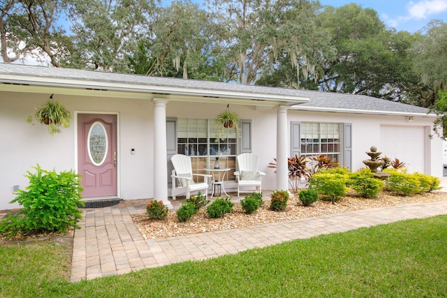 property entrance with a garage, a yard, and covered porch