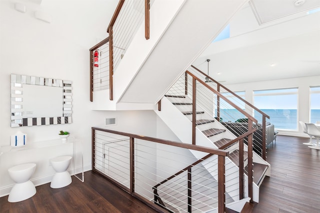 stairs with visible vents, baseboards, wood finished floors, and a water view