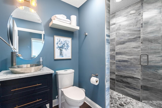 full bathroom featuring vanity, baseboards, a shower stall, a textured ceiling, and toilet